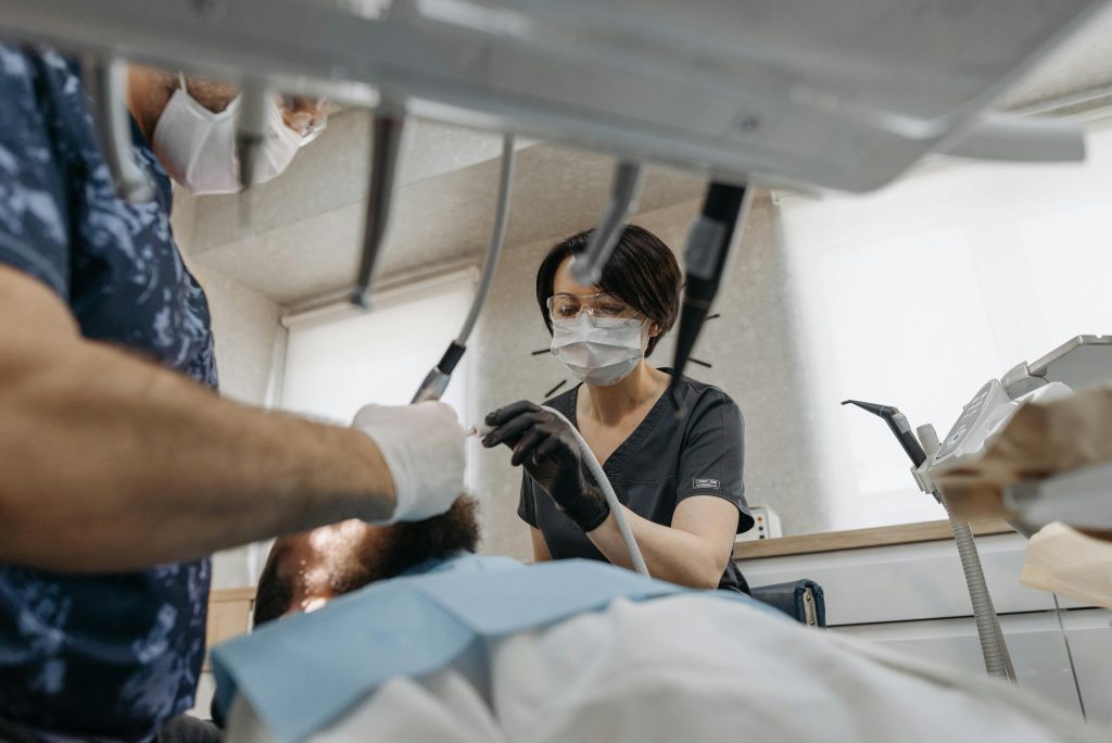 A dentist working diligently on a patient in a dental clinic, focusing on oral care while wearing protective gear.